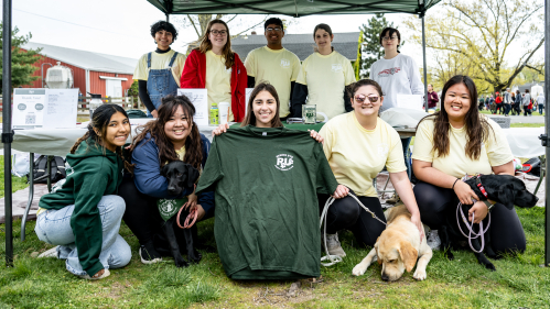 Members of the Seeing Eye Puppy Raising Club pose with three puppies.
