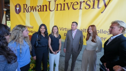 Matthew Edson and students in front of a Rowan University banner.